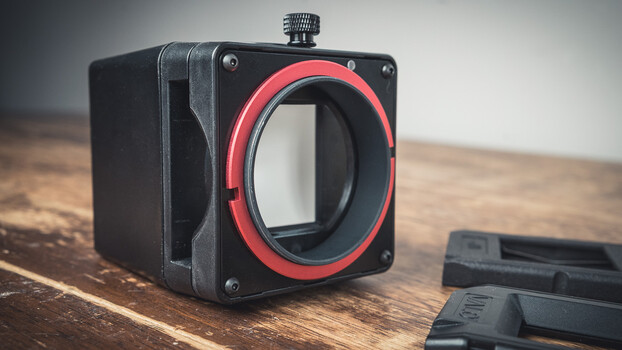 Mirrorless camera body with red accent ring on wooden surface
