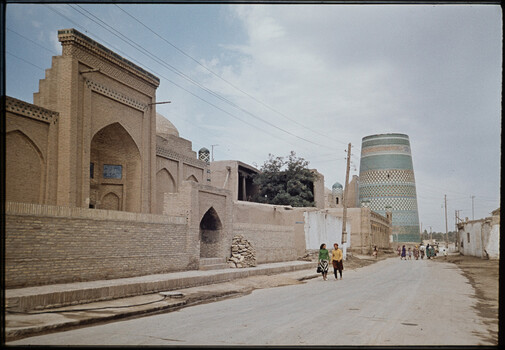 Ornate brick mosque and turquoise ceramic tower in a Central Asian city street