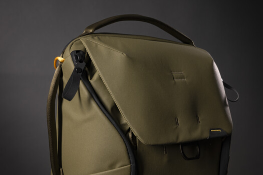 Tan and black camera bag with flap closure and shoulder strap against gray background