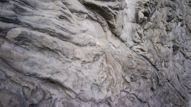 Close-up of layered stone surface with flowing, wave-like erosion patterns and texture