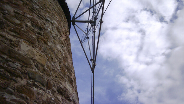 Cellular transmission tower with antennas mounted on stone masonry structure against cloudy sky