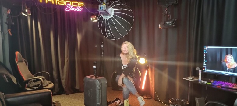 Woman posing in professional studio with large parabolic softbox and key light