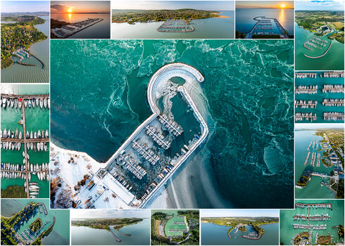 Aerial view of a large curved marina with boat slips arranged in a horseshoe pattern surrounded by turquoise water