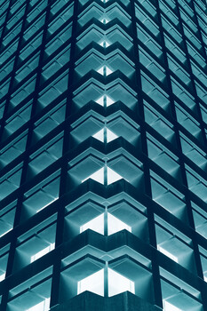 Symmetrical view of modern glass building facade with centered vertical pattern of illuminated windows