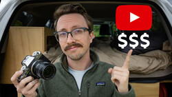 Man holding vintage film camera inside a van, pointing at YouTube and dollar sign graphics overlay.