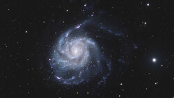 Spiral galaxy with bright central core and sweeping blue arms against starfield.