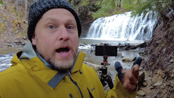 Content creator recording at a waterfall with smartphone mounted on tripod.