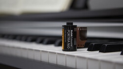 Kodak Portra 160 film canister placed on piano keys with blurred background.