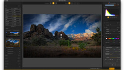 Desert landscape with rocky peaks and snow-capped mountains under blue sky, shown in photography editing software.