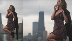Woman in patterned dress and black cardigan posing against urban skyline with tall buildings.