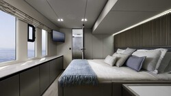 Modern luxury yacht cabin with panoramic ocean views, queen bed with gray upholstered headboard, and integrated storage cabinetry.