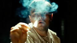 Man with dramatic lighting smoking cigarette against dark background.