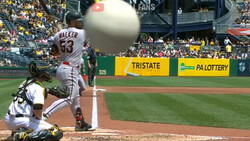 Baseball batter at plate during pitch, ball in motion, catcher and umpire visible behind.