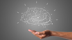 Illustration of a brain rendered in white outline floating above an open palm against a gray background.