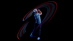 Golfer mid-swing photographed with light painting technique creating red and blue motion trails against black background.