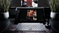 Laptop and desktop monitor displaying film poster designs in a creative workspace with potted plants and microphone.