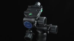 Professional fluid head tripod with panoramic lock, pan/tilt handles, and bubble level indicators on dark background.