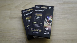 Three black boxes of Exascend Catalyst CompactFlash memory cards with 128GB capacity displayed on a wooden surface.
