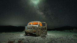 Abandoned rusted truck cab under starry night sky with Milky Way visible overhead.