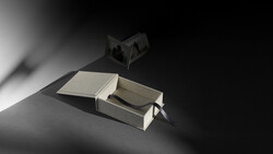 Open book with pages casting sharp shadows under dramatic directional lighting against a dark background.