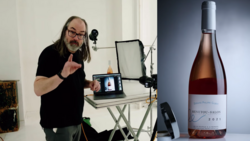 Man with long hair and glasses gestures while speaking into a microphone during a video production setup.