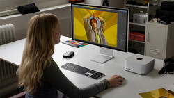 Designer working on portrait photo editing in Adobe Lightroom with vibrant yellow background on monitor.