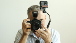 Photographer holding a Fujifilm film camera with an action camera mounted on top.