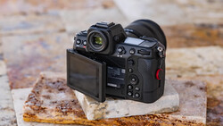 Professional mirrorless camera displayed on a weathered concrete block, showing rear LCD screen and control layout.