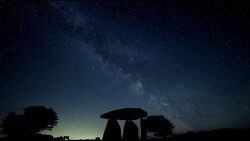 Silhouetted ancient stone structure against night sky filled with Milky Way stars.
