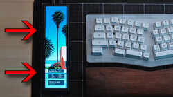 Smartphone displaying a tropical beach scene with palm trees and time stamp, positioned next to a white mechanical keyboard on a wooden desk.