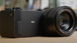 Sigma dp3 compact camera with attached macro lens displayed on neutral surface.