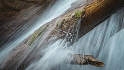 Flowing water cascades over layered rock formations with silky motion blur effect.
