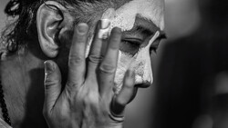 Man's face in profile with hand covering part of his face, shot in black and white.