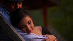 Woman resting her head against a man's shoulder in soft, warm lighting.