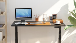 Minimalist home office desk setup with monitor, supplies, and natural window lighting.