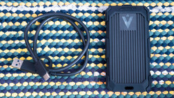 External SSD with USB cable on a patterned textile background.