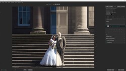Bride and groom posing on grand stone steps of a classical building with columns and tall windows.