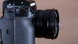 Mirrorless camera with attached zoom lens against a neutral beige background.