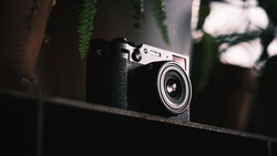Vintage rangefinder camera with black leather body and chrome top plate resting on a dark surface.