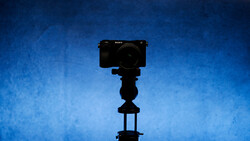 Sony mirrorless camera mounted on a tripod against a deep blue textured background.