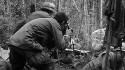 Black and white photograph of film crew members operating camera equipment in a wooded outdoor setting.