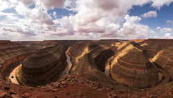 Aerial view of two dramatic horseshoe bends carved by a winding river through layered desert canyon walls.