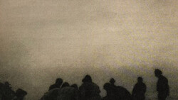 Silhouettes of people standing against a hazy, overexposed sky during what appears to be low-visibility conditions.
