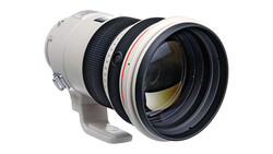 White and black telephoto lens with internal focus mechanism and rounded front element.