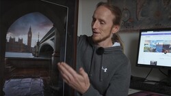 Photographer reviewing a large-format print of Big Ben and Westminster Bridge displayed on a monitor in a studio workspace.