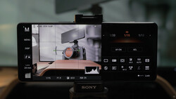 Sony mirrorless camera display showing live view of a professional camera on a wooden table with studio lighting setup.
