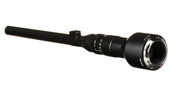 Black rifle scope with extended objective lens and adjustment turrets against white background.