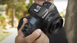 Photographer holding a Canon EOS R5 mirrorless camera with a Canon RF lens and wireless flash trigger mounted on top.