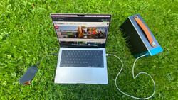 Laptop displaying a video streaming interface with an external hard drive connected via USB cable on grass.