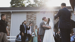 Bride and groom kissing during outdoor wedding ceremony with guests watching.